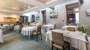 Un restaurant avec des tables rondes, des chaises et un sol recouvert de moquette.