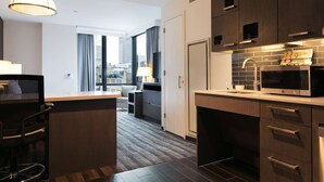 Una cocina moderna con armarios de madera oscura, un microondas y un ventanal con vistas a la ciudad.