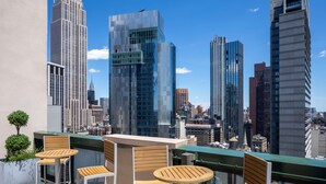 Una terraza en la azotea con vistas al horizonte de la ciudad, incluyendo el Empire State Building.