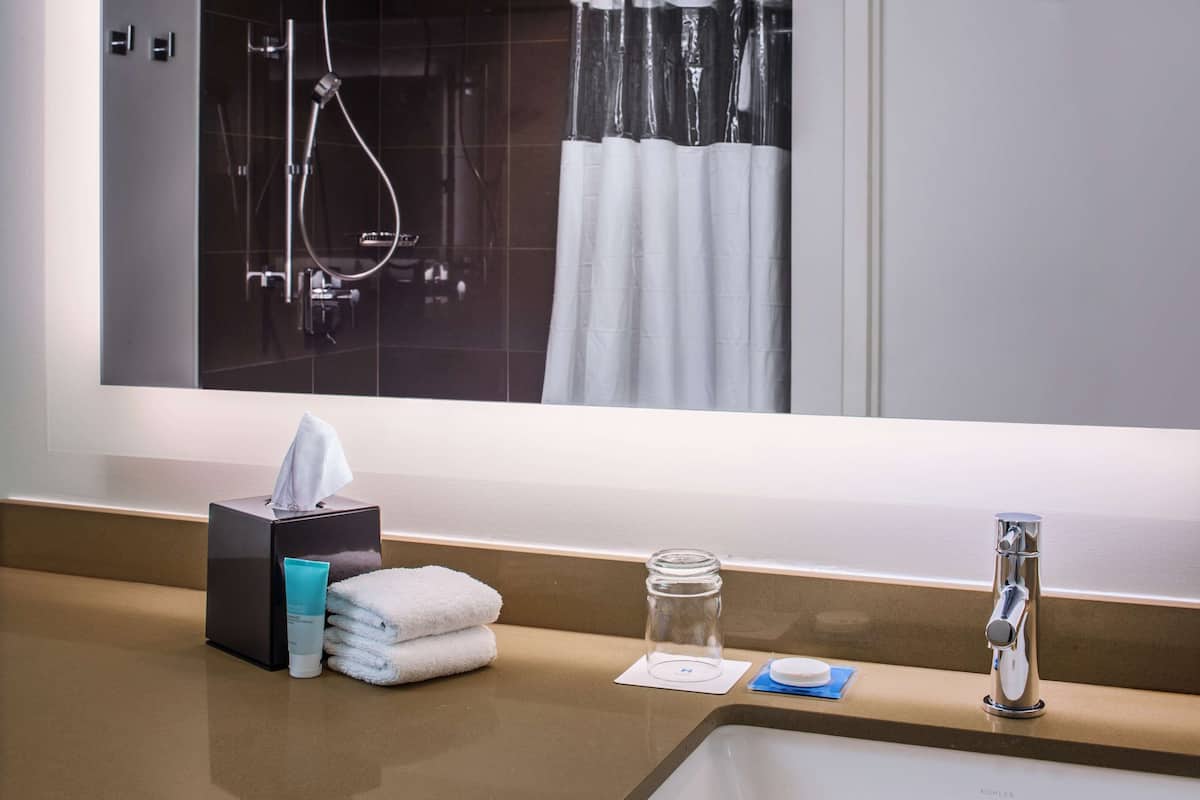 A bathroom with a sink, mirror, and a shower area.