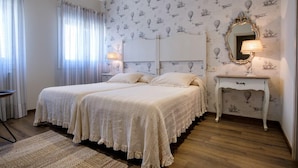 A bedroom with two beds, a nightstand, a mirror, and a patterned wallpaper. - La Casona de Nené (Arzua)