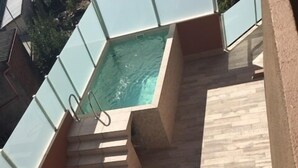 A modern outdoor pool area with a hot tub, a set of stairs leading to a higher level, and two lounge chairs on a grassy patch. - La Casona de Nené (Arzua)