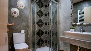 A modern bathroom with a glass shower enclosure, a toilet, a sink, and decorative plates on the wall. - La Casona de Nené (Arzua)