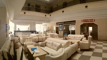 A spacious lobby with multiple seating areas, a reception desk, and a sign for 'BAYAR Construction & Real Estate'.