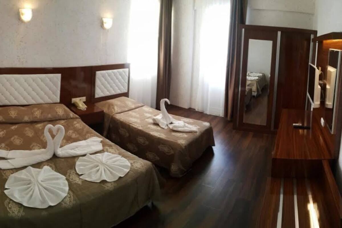 Two single beds with headboards, a wooden floor, and a mirror on the wall.