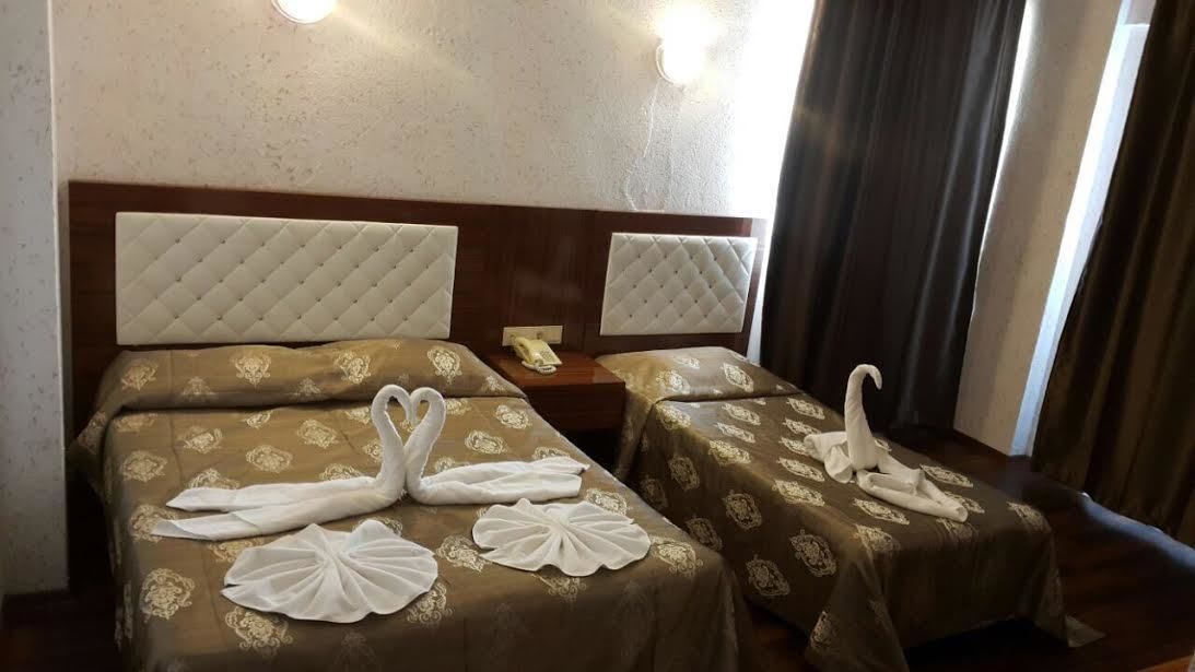 Camera d'albergo con due letti, ciascuno con testiera e comodino. Asciugamani disposti sui letti.