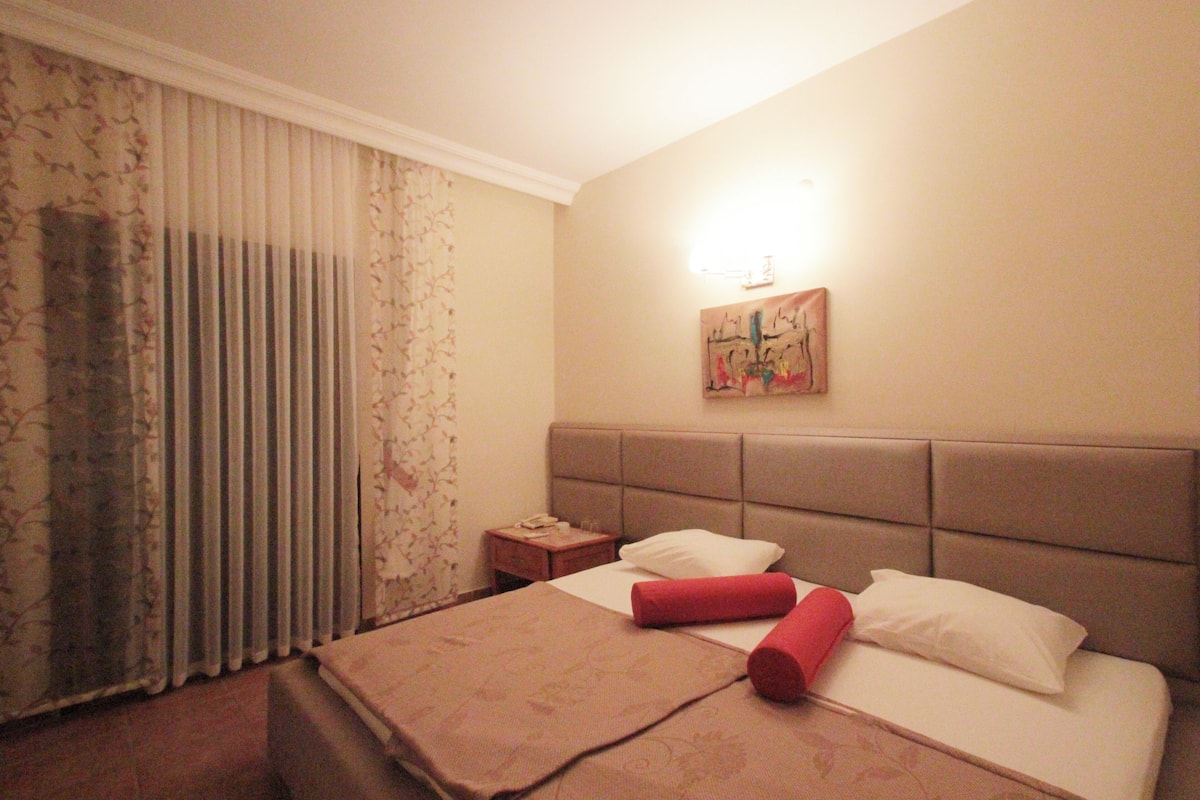 Une chambre d’hôtel avec un lit, une table de chevet, une lampe et un tableau au mur.