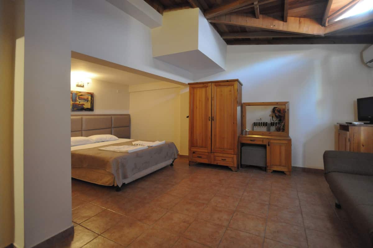 Une chambre à coucher comprenant un lit, une armoire en bois, un bureau et un téléviseur.