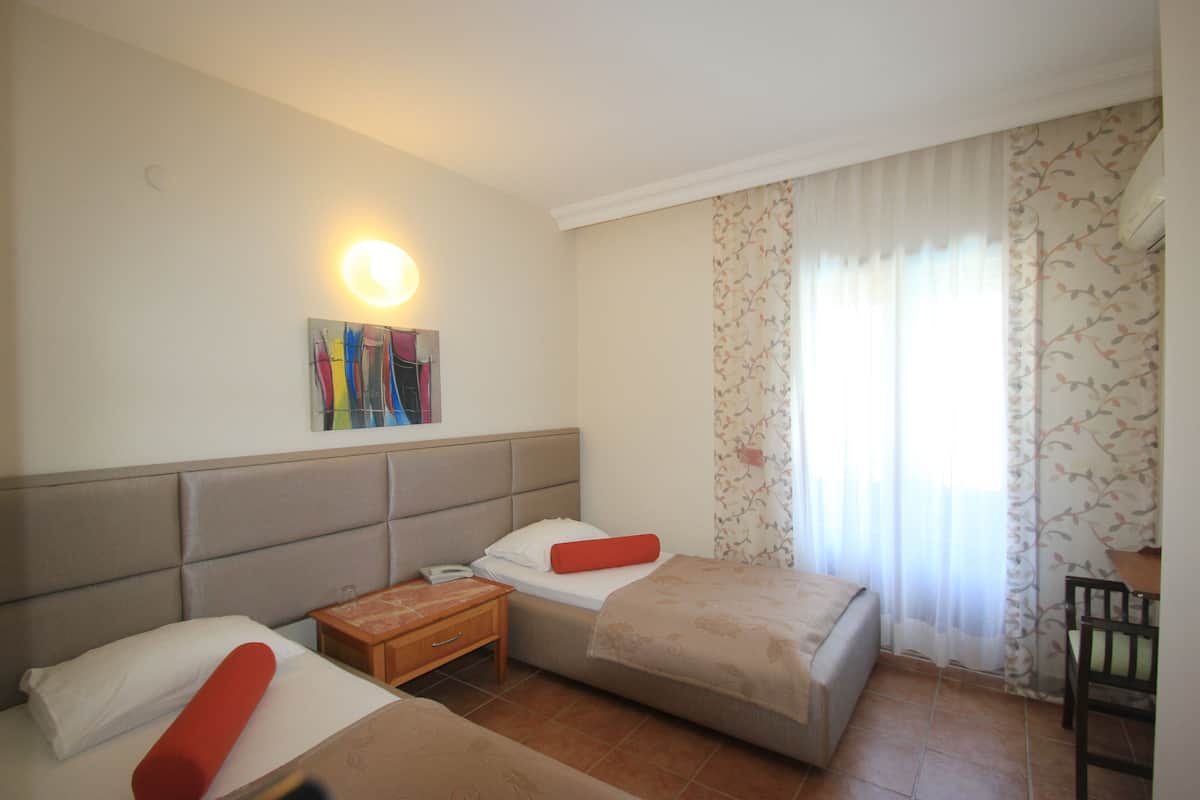 Une chambre d’hôtel avec deux lits, une table de chevet, une petite table et une chaise.