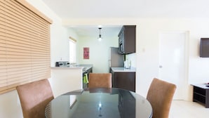Un espace de vie compact comprenant un coin repas, une kitchenette et un petit téléviseur fixé au mur.