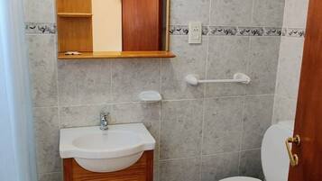 A bathroom with a wooden vanity, a sink, a mirror, and a toilet.