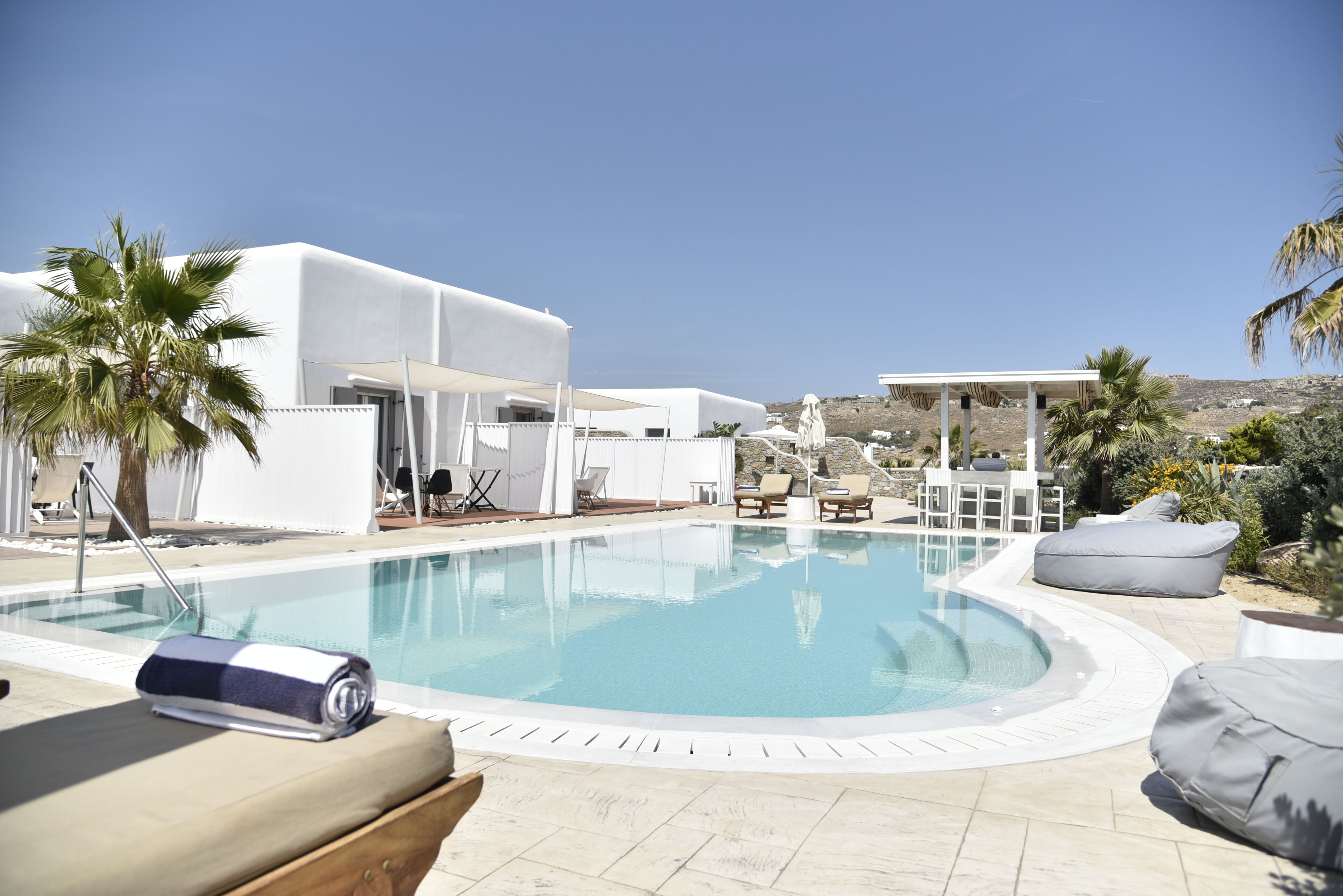 Uma área de piscina moderna com espreguiçadeiras e um edifício branco.
