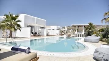 Uma área de piscina moderna com espreguiçadeiras e um edifício branco.