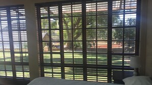 A room with a bed, a nightstand, and a window with blinds. - The Cradle Rest (Muldersdrift)
