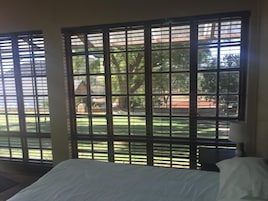 Una habitación con cama, mesita de noche y ventana con persianas.