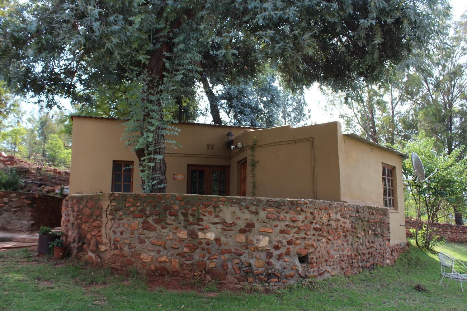 Un edificio de paredes de piedra con techo plano, un pequeño porche y una antena parabólica.
