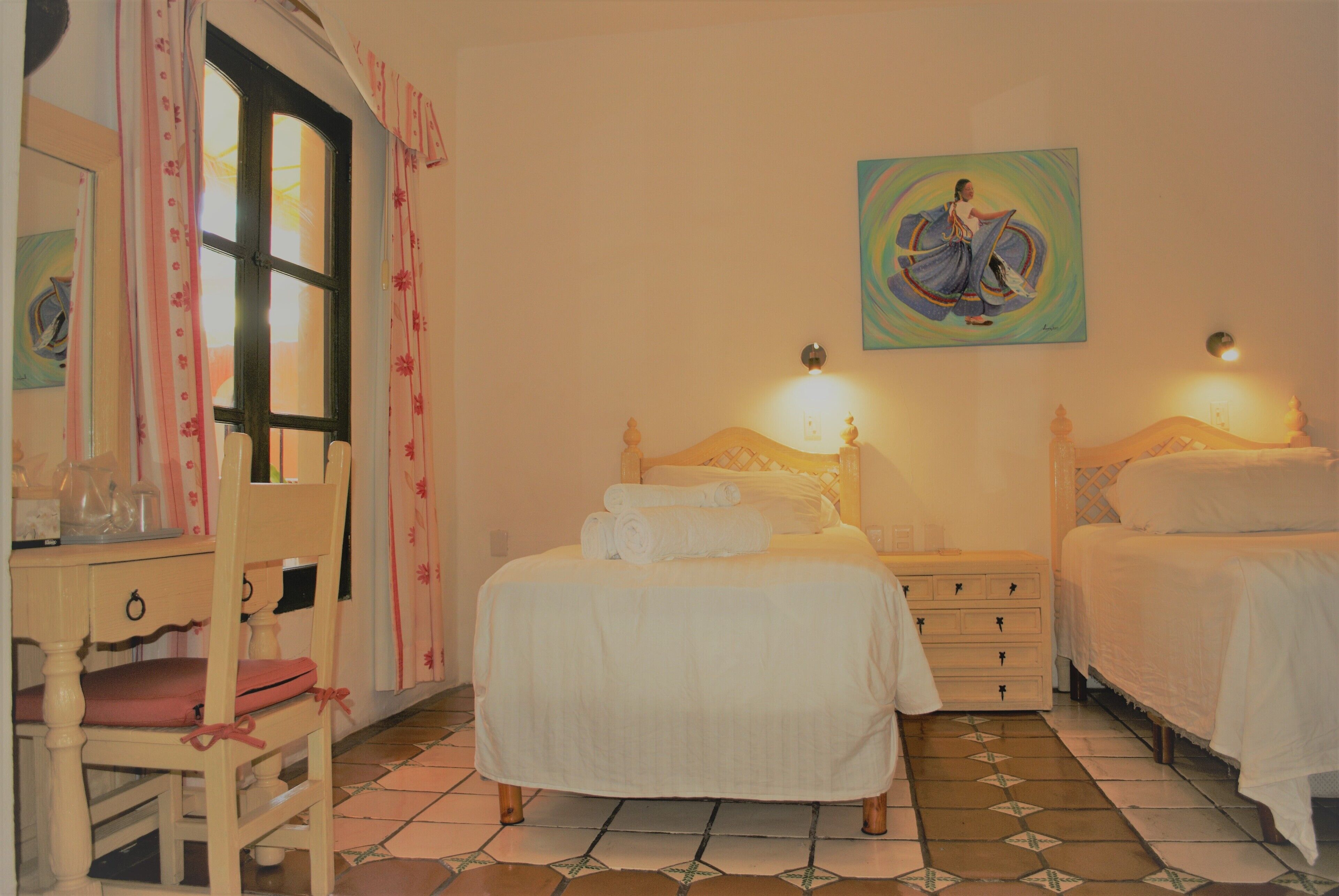 A bedroom with two beds, a chair, a dresser, and a painting on the wall.