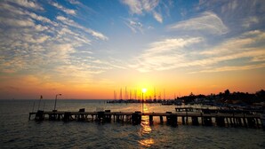 A sunset over a marina with boats and a pier extending into the water. - Hotel Belmar (Isla Mujeres)