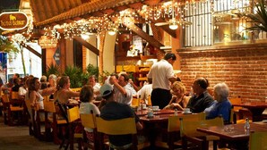 A restaurant with outdoor seating, brick walls, and string lights. - Hotel Belmar (Isla Mujeres)