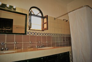 Casa de banho com painel de azulejos, espelho, cortina de chuveiro e janela.