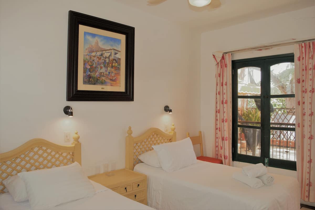 A hotel room with two beds, a framed picture on the wall, and a window with curtains.