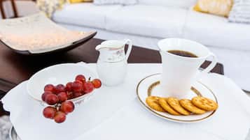 A white table with a white pitcher, a bowl of red grapes, and a plate of biscuits.