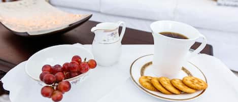 Una mesa blanca con una jarra blanca, un cuenco de uvas rojas y un plato de galletas.