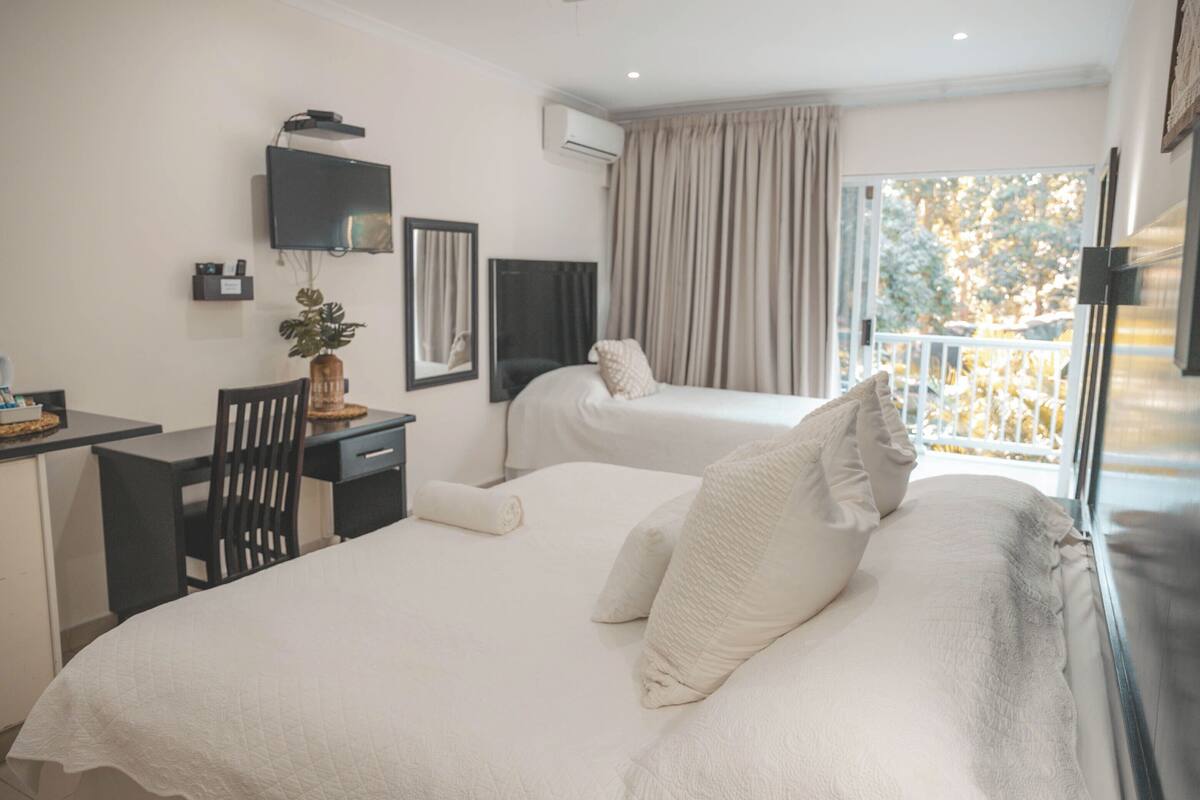 Une chambre d’hôtel avec deux lits, un bureau, une télévision et un balcon avec vue.