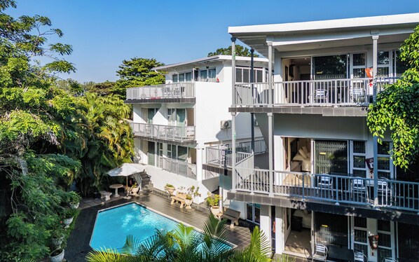A multi-story hotel with a swimming pool, balconies, and lush greenery. - Beside Still Waters Boutique Hotel (Umhlanga)