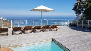 A wooden deck with lounge chairs and a pool, overlooking a coastline with a clear view of the ocean. - Headlands House Guest Lodge (Knysna)
