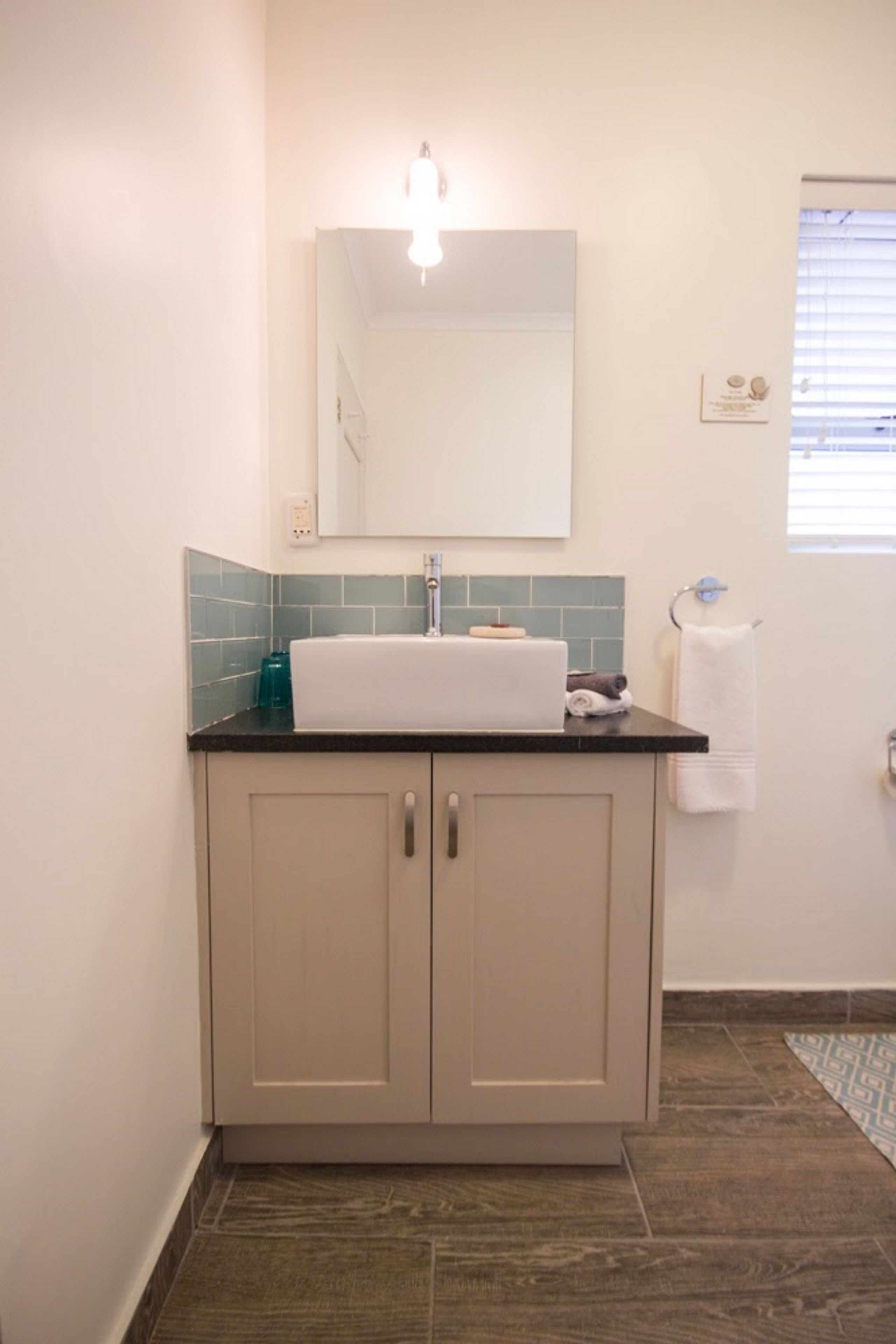 A bathroom with a sink, mirror, and towel rack.