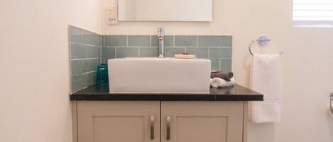 A bathroom with a sink, mirror, and towel rack.