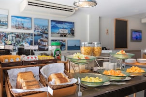 Buffet com diversos alimentos e seleção de pães.
