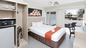 A hotel room with a bed, a desk, a chair, a wardrobe, and a balcony with a view of a park. - Casa Andina Standard Talara (Pariñas)