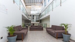 A spacious lobby with a high ceiling, a central seating area with sofas, and potted plants. - Casa Andina Standard Talara (Pariñas)