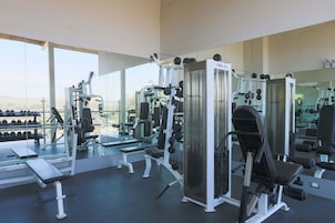 Uma academia com diversos equipamentos de exercício, bancos e halteres.