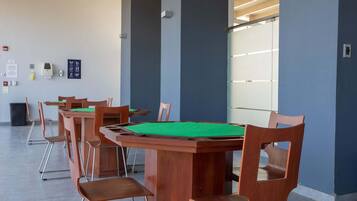 A conference room with a wooden table and chairs, a green felt tablecloth, and a whiteboard with writing.