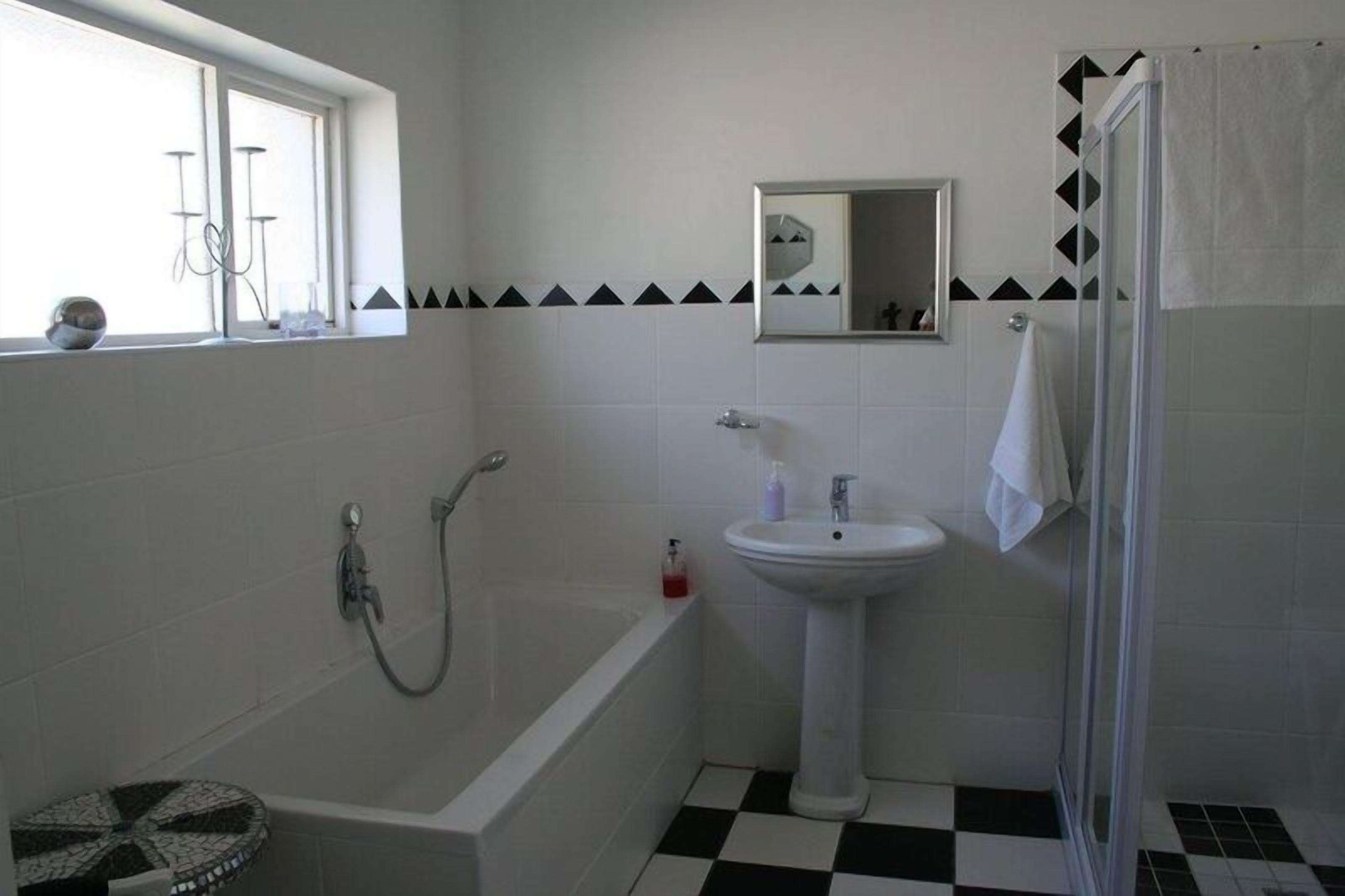 Un baño con bañera, lavabo, espejo y ducha.