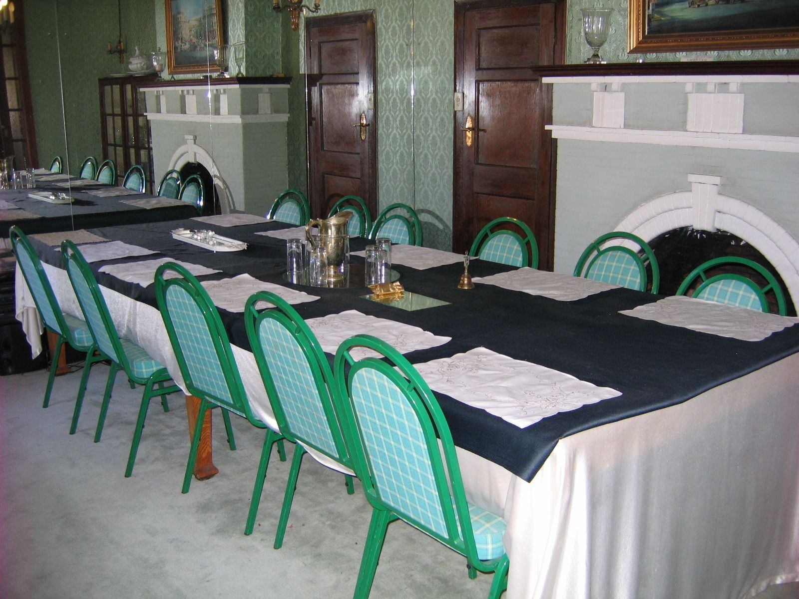 A dining room with a long table set for a meal, surrounded by green chairs.