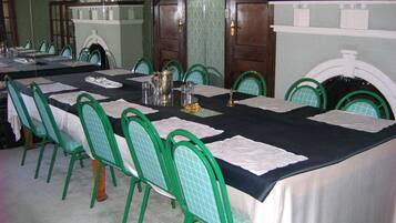 A dining room with a long table set for a meal, surrounded by green chairs.