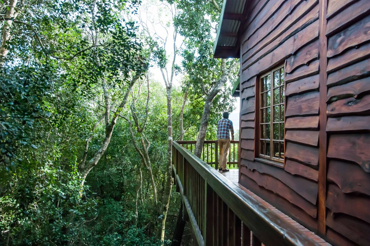 Una cabaña de madera con un balcón que da a un área boscosa.