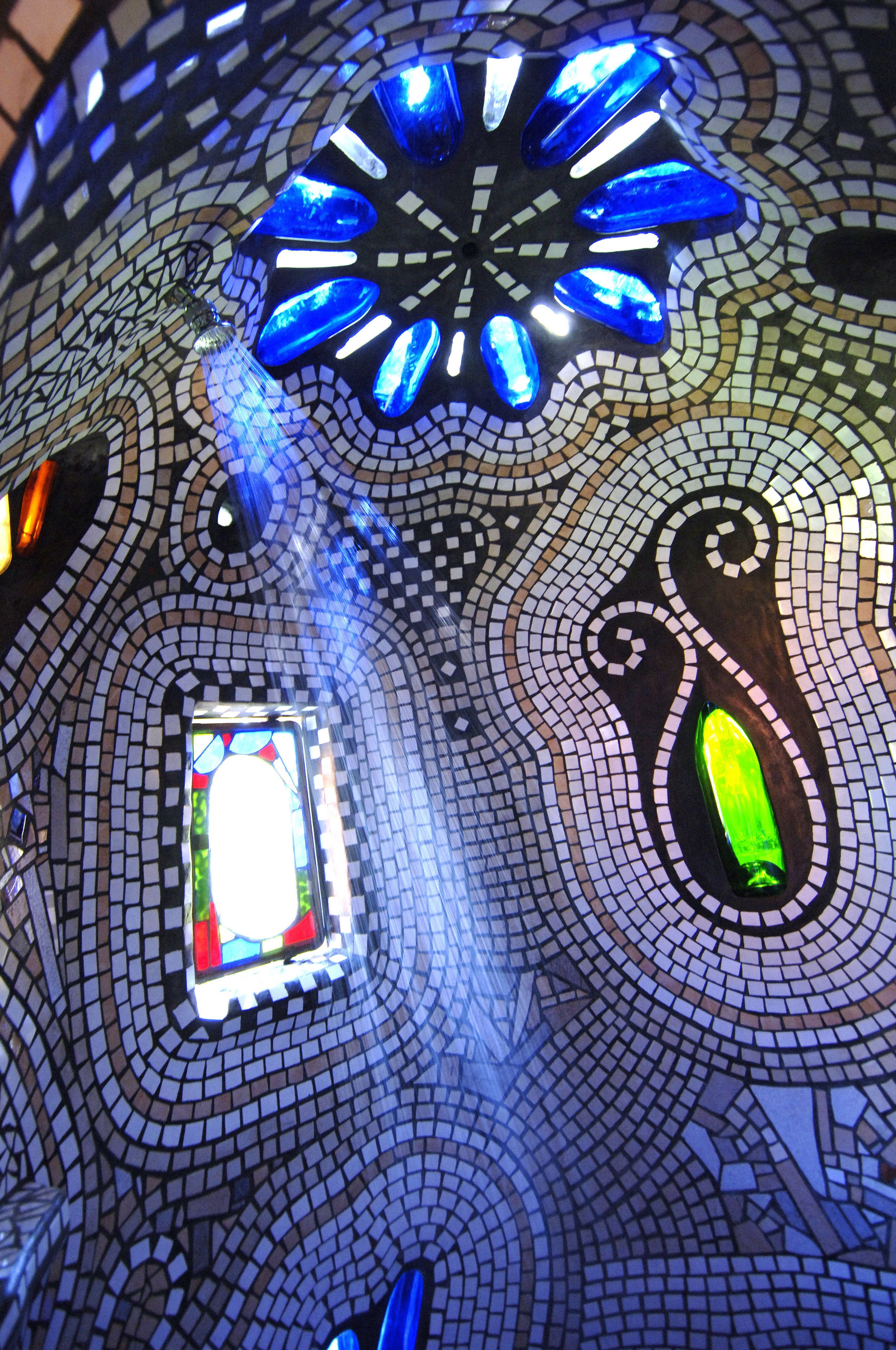 A mosaic ceiling with geometric patterns and a central stained glass window.