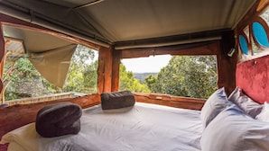 A cozy room with a bed, a window with a view of greenery, and a wooden ceiling. - Moon Shine on Whiskey Creek (The Crags)