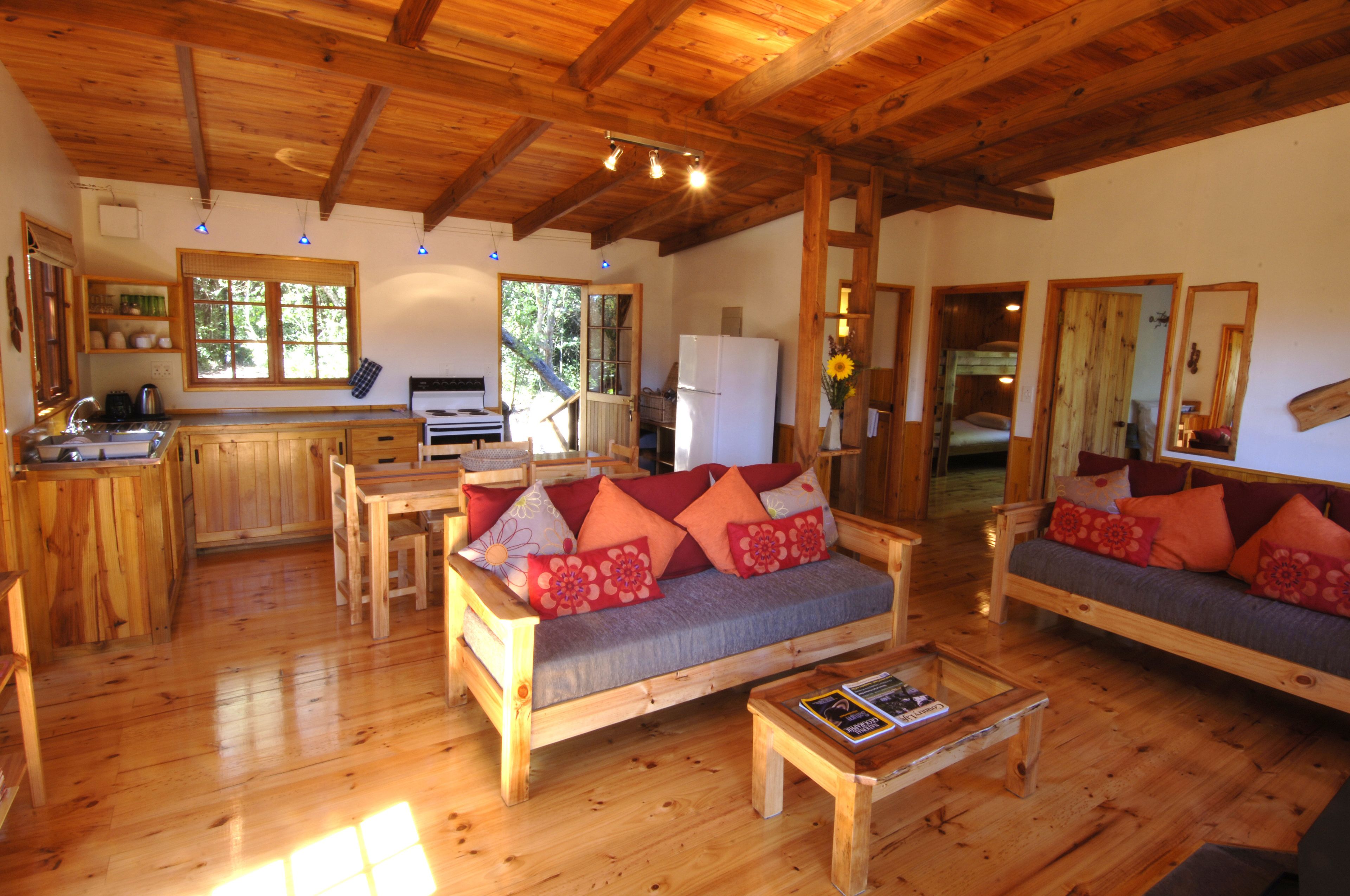 A wooden interior with a sofa, coffee table, and kitchen area.