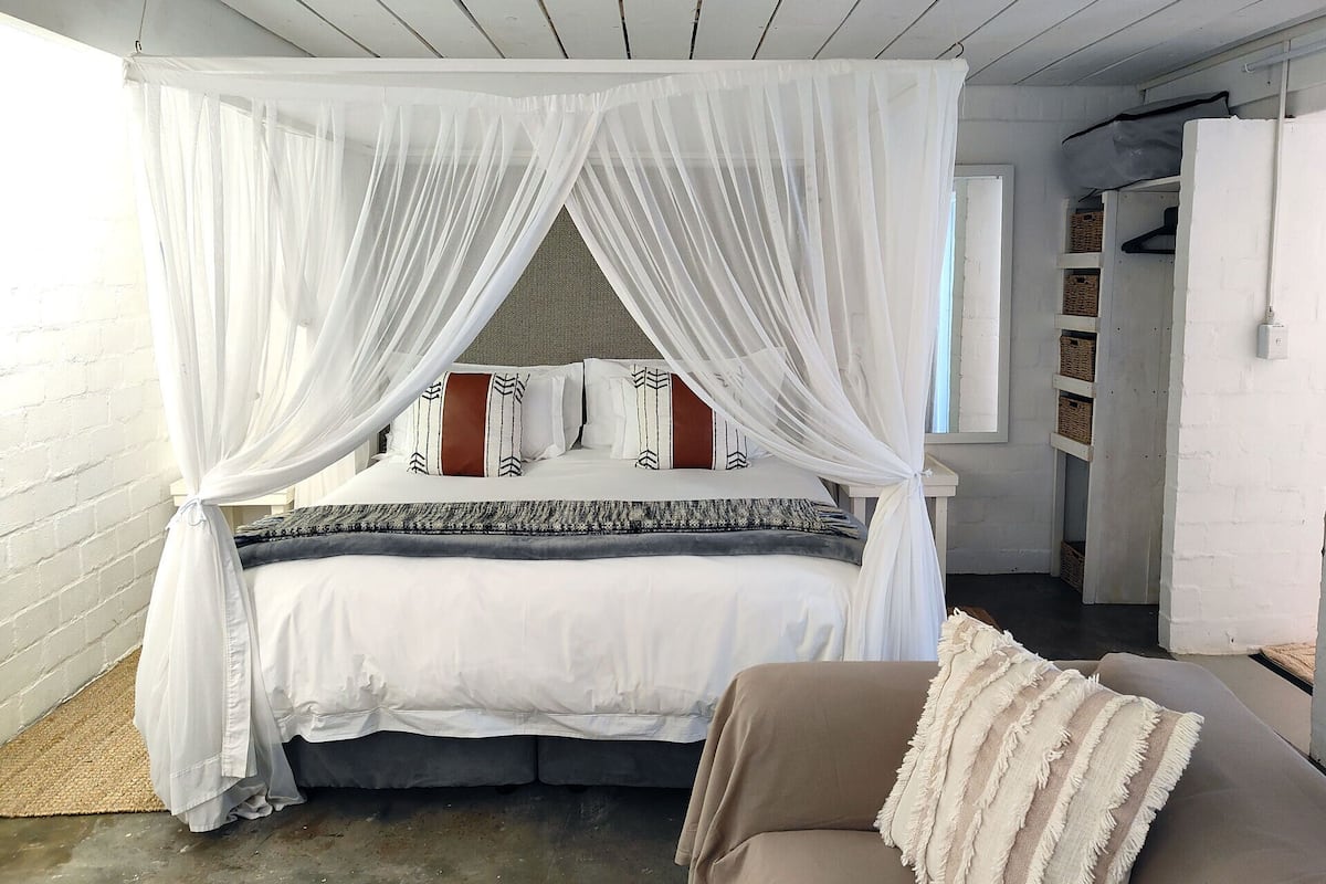 A bedroom with a four-poster canopy bed, a bedside table, and a wardrobe.