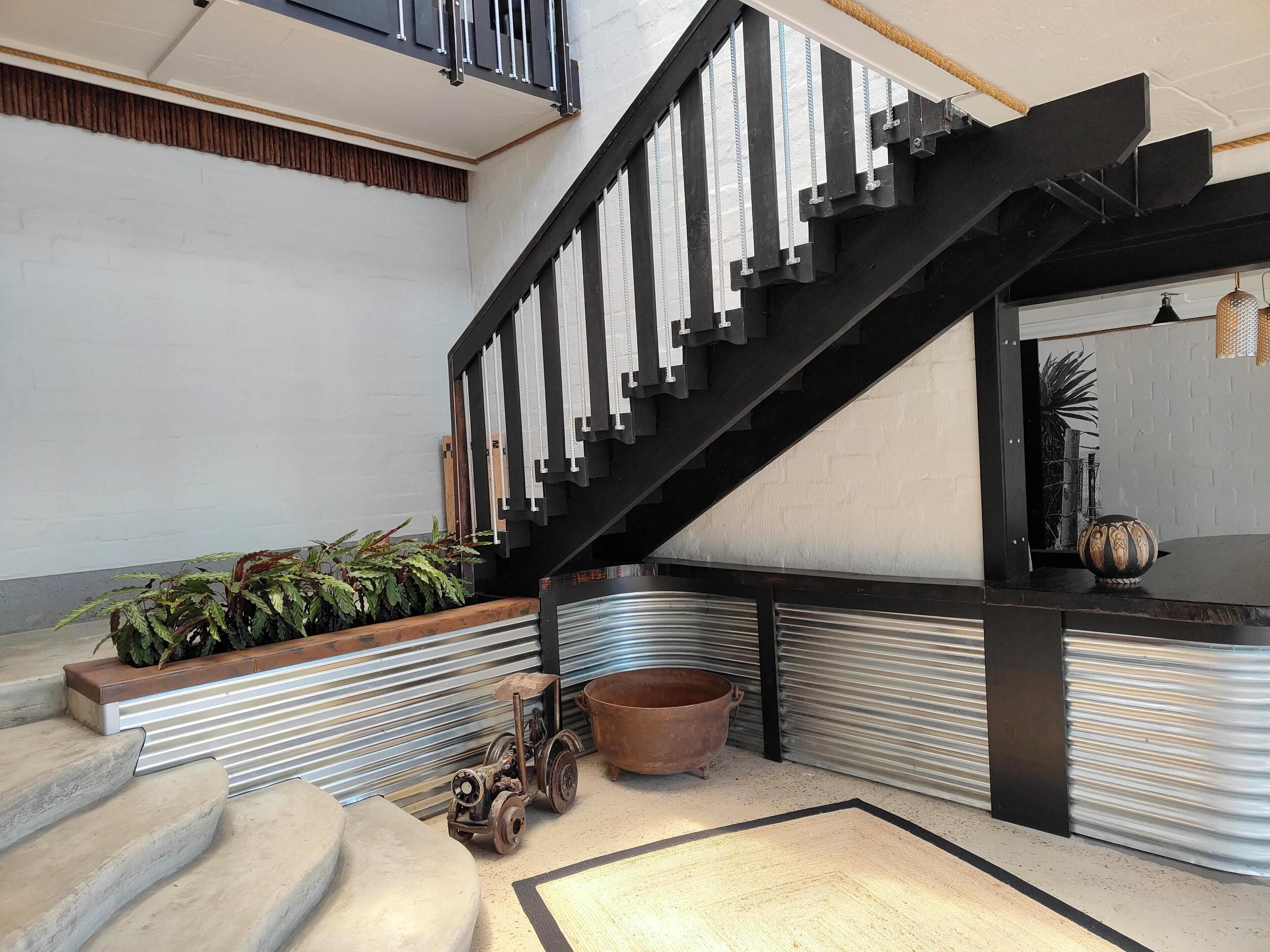 A modern interior with a black staircase, a metal railing, and a potted plant.