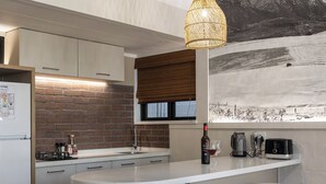 Een moderne keuken met een groot schiereiland, witte barstoelen, een hanglamp en een muurschildering van een besneeerd landschap.