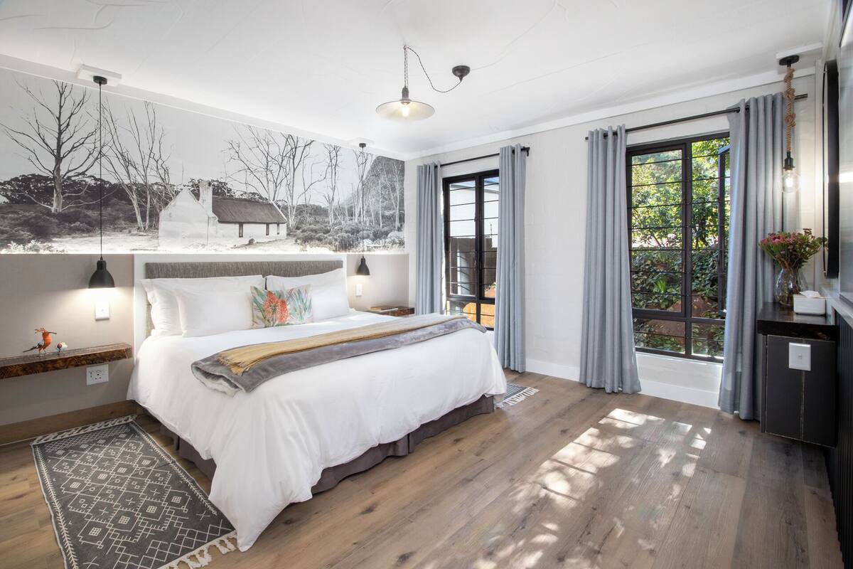 A modern bedroom with a large bed, a view of the outdoors, and a rustic decor style.