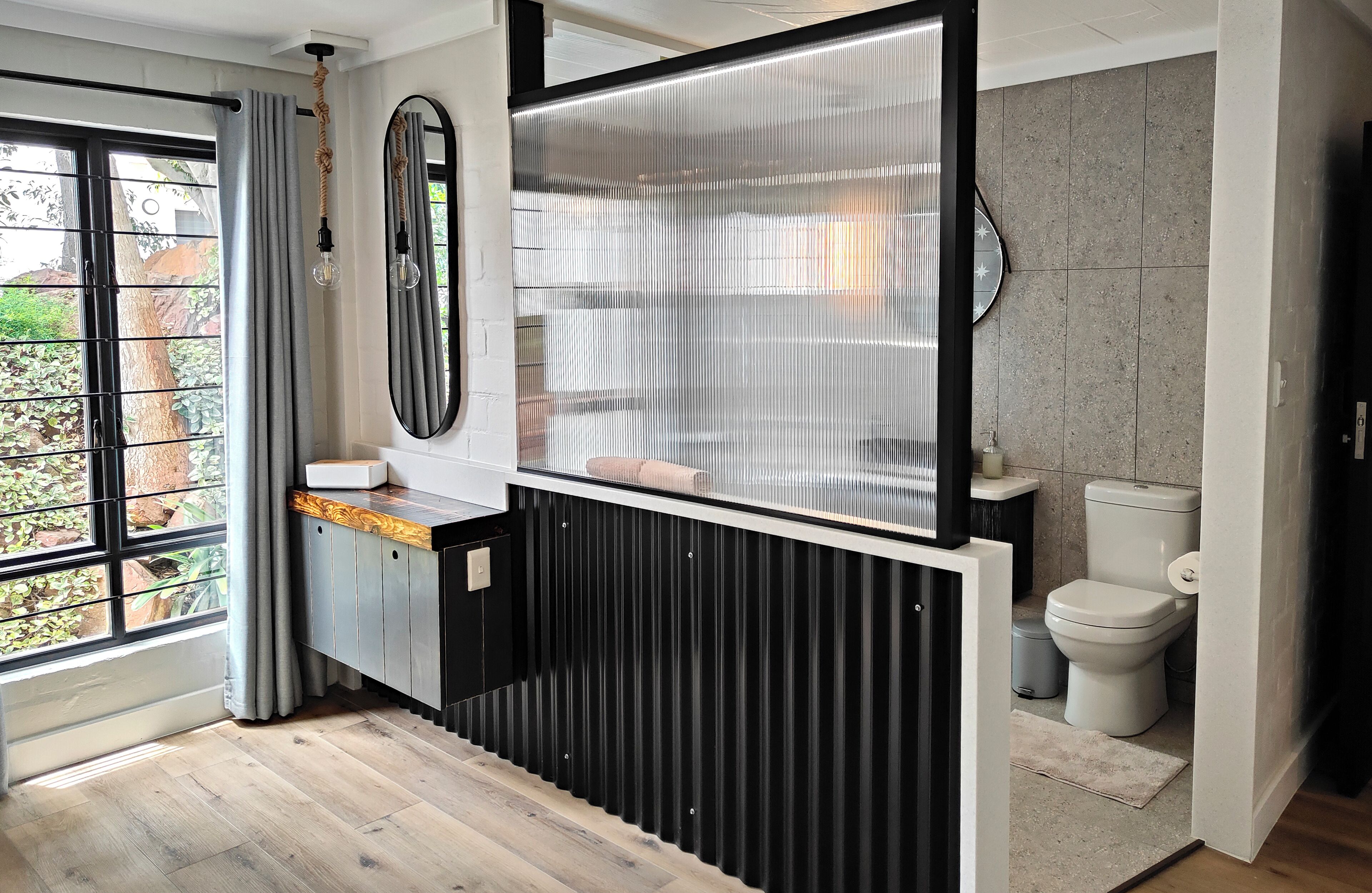 Une salle de bain moderne avec une grande fenêtre, un miroir, des toilettes et un lavabo.
