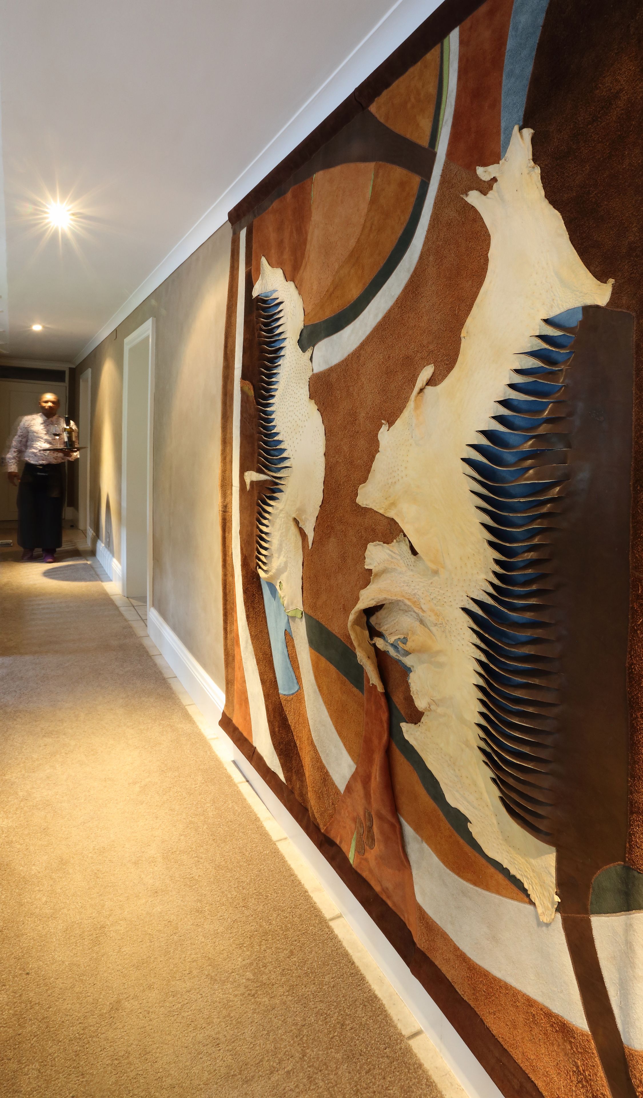 A hallway with a large wall mural featuring indigenous art.